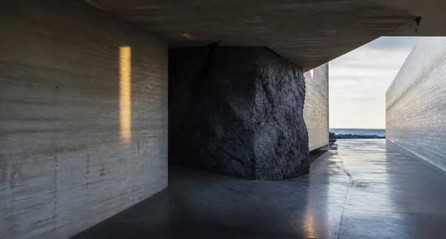A dark rock framed by concrete walls with an opening towards the sea